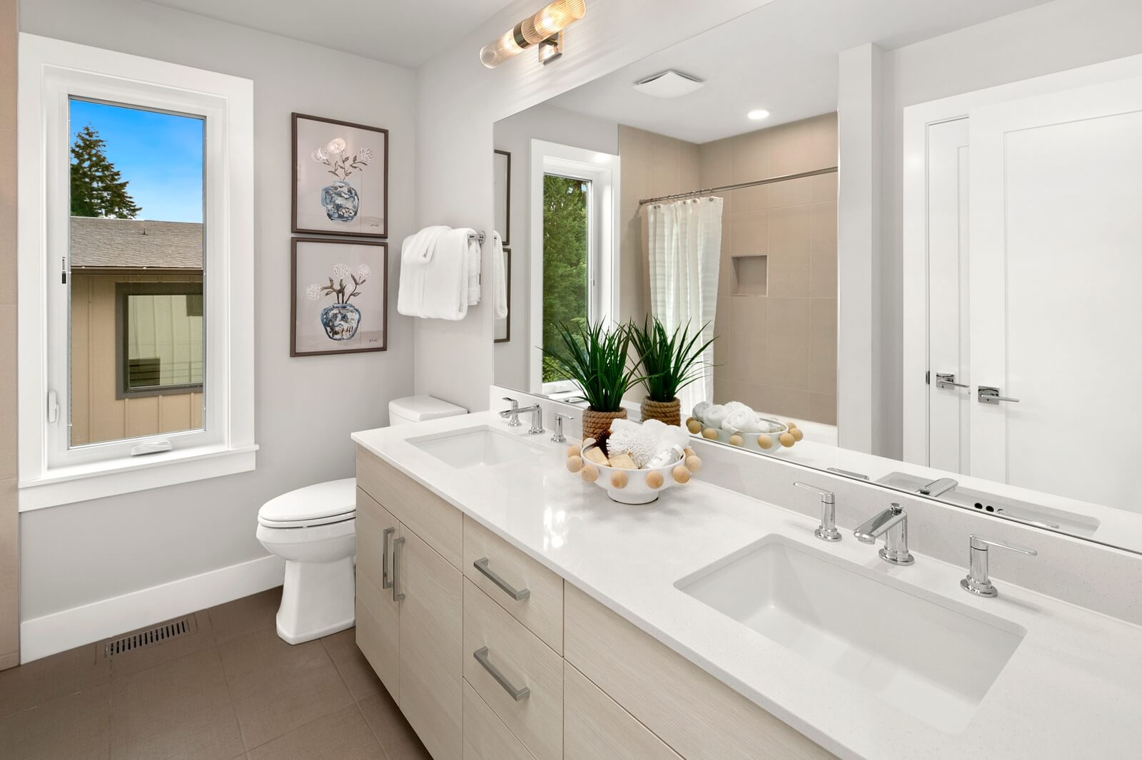 Bright full bath with dual sinks and tiled shower