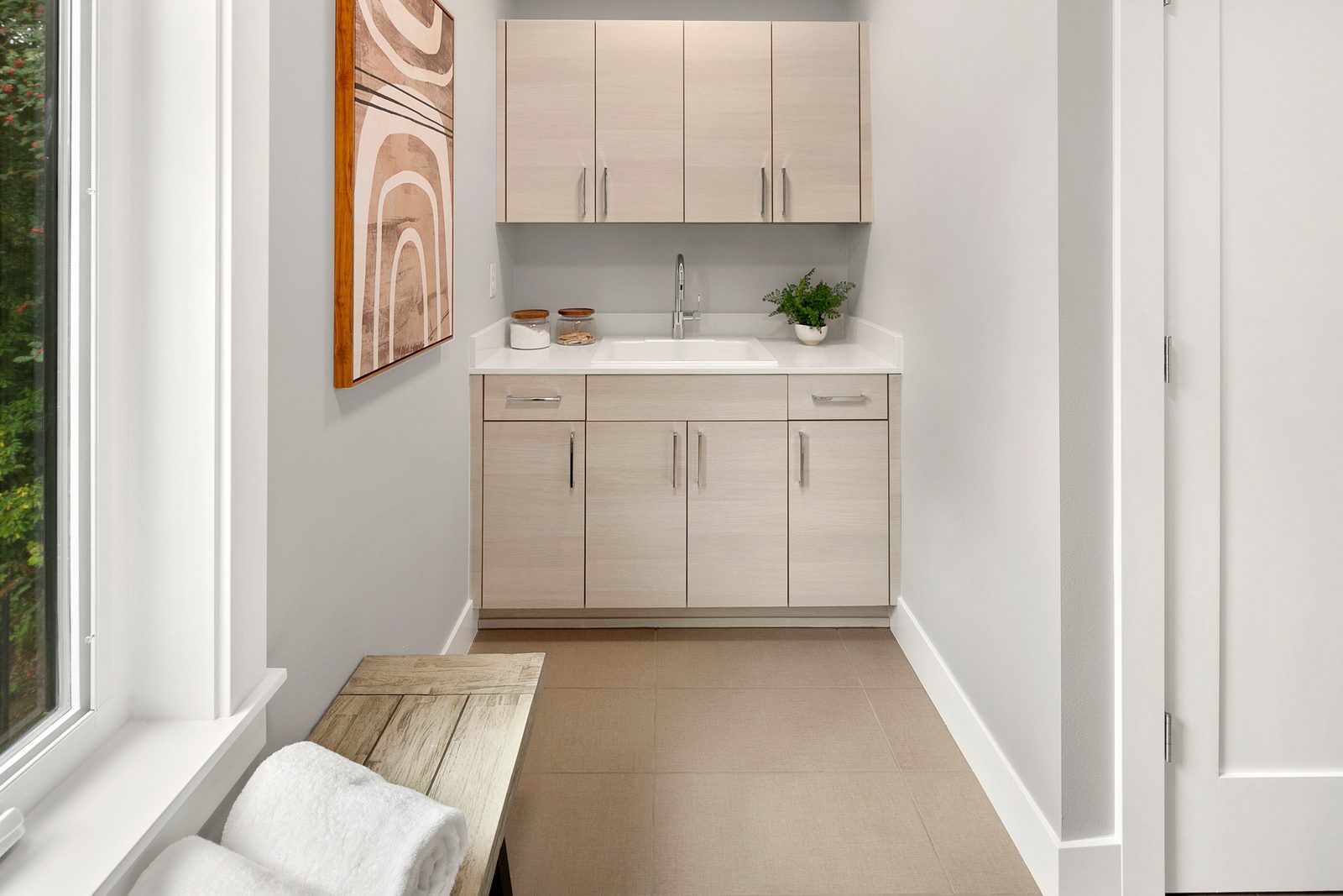 Spacious laundry area with built-in cabinetry, sink, and storage.