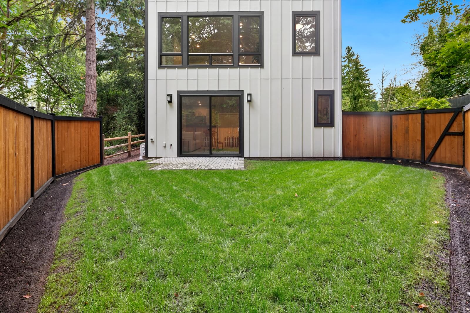 Spacious fenced yard bordered by greenery